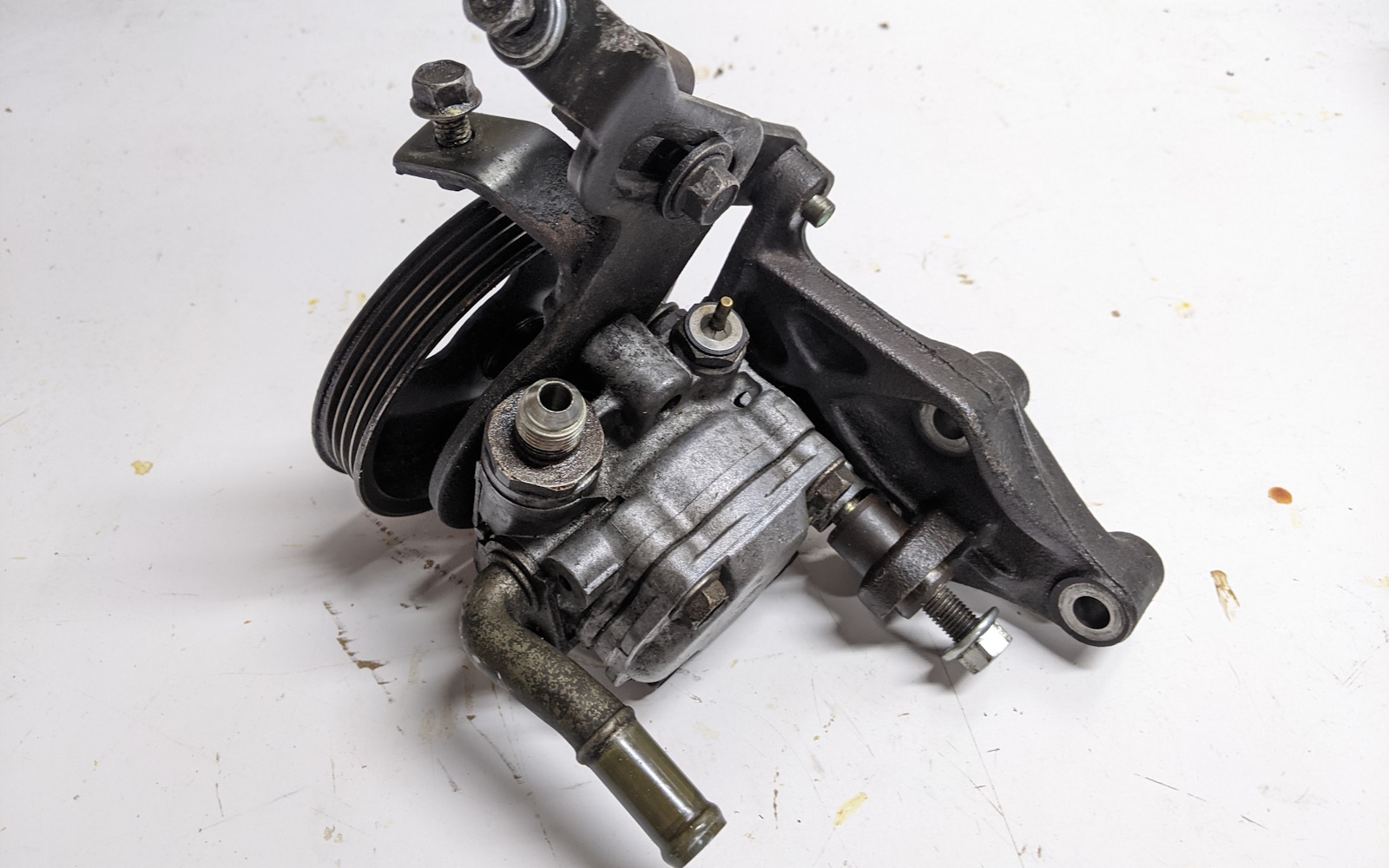 Power steering pump with mounting bracket and tensioner